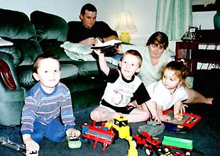 （左）おもちゃで遊ぶ長男のケネスちゃん（左）、二男のア ンドリューちゃん（中央）、長女のヘザーちゃんを見つめるダンカ ンさん夫妻（スコットランド・クラックマナン市）