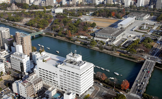 The Chugoku Shimbun building (the white building in the foreground) stands across the river from Peace Memorial Park.